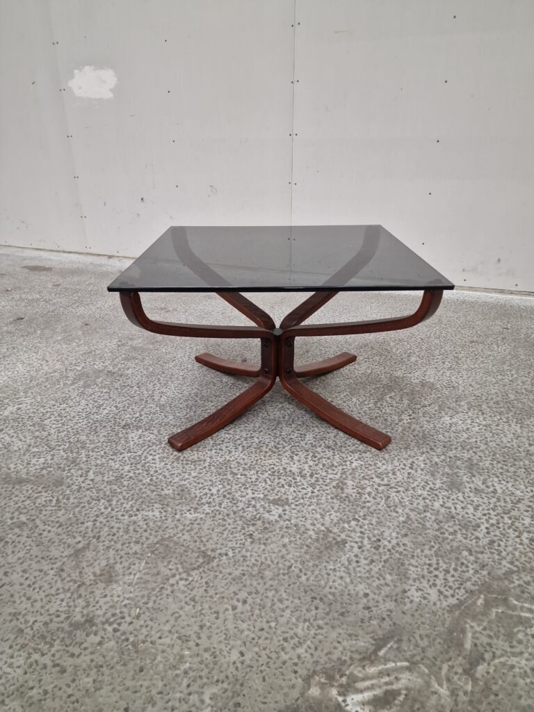 Mid-century modern coffee table with smoked glass top and curved wooden base.