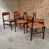 Mid-century modern rosewood dining chairs with worn orange leather.