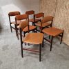 Mid-century modern rosewood dining chairs with leather upholstery.