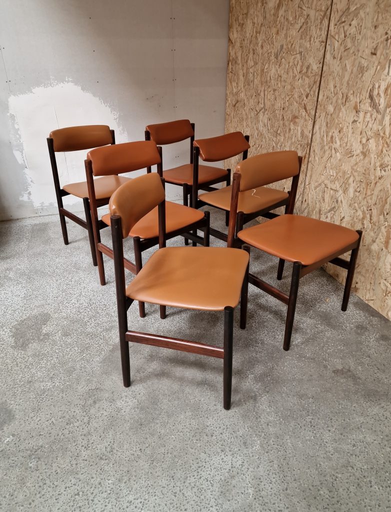 Mid-century modern rosewood dining chairs with leather upholstery.