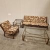 Mid-century modern rattan furniture set: sofa, armchair, and glass-topped tables.