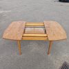 Extendable light wood dining table with rounded edges.