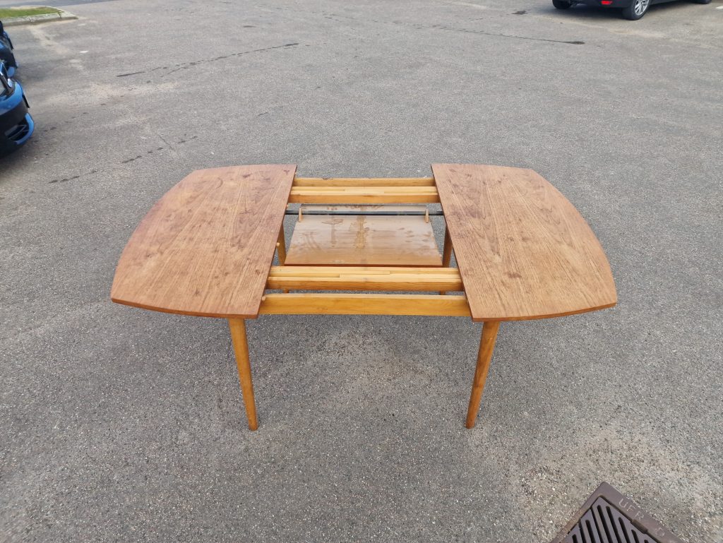 Extendable light wood dining table with rounded edges.